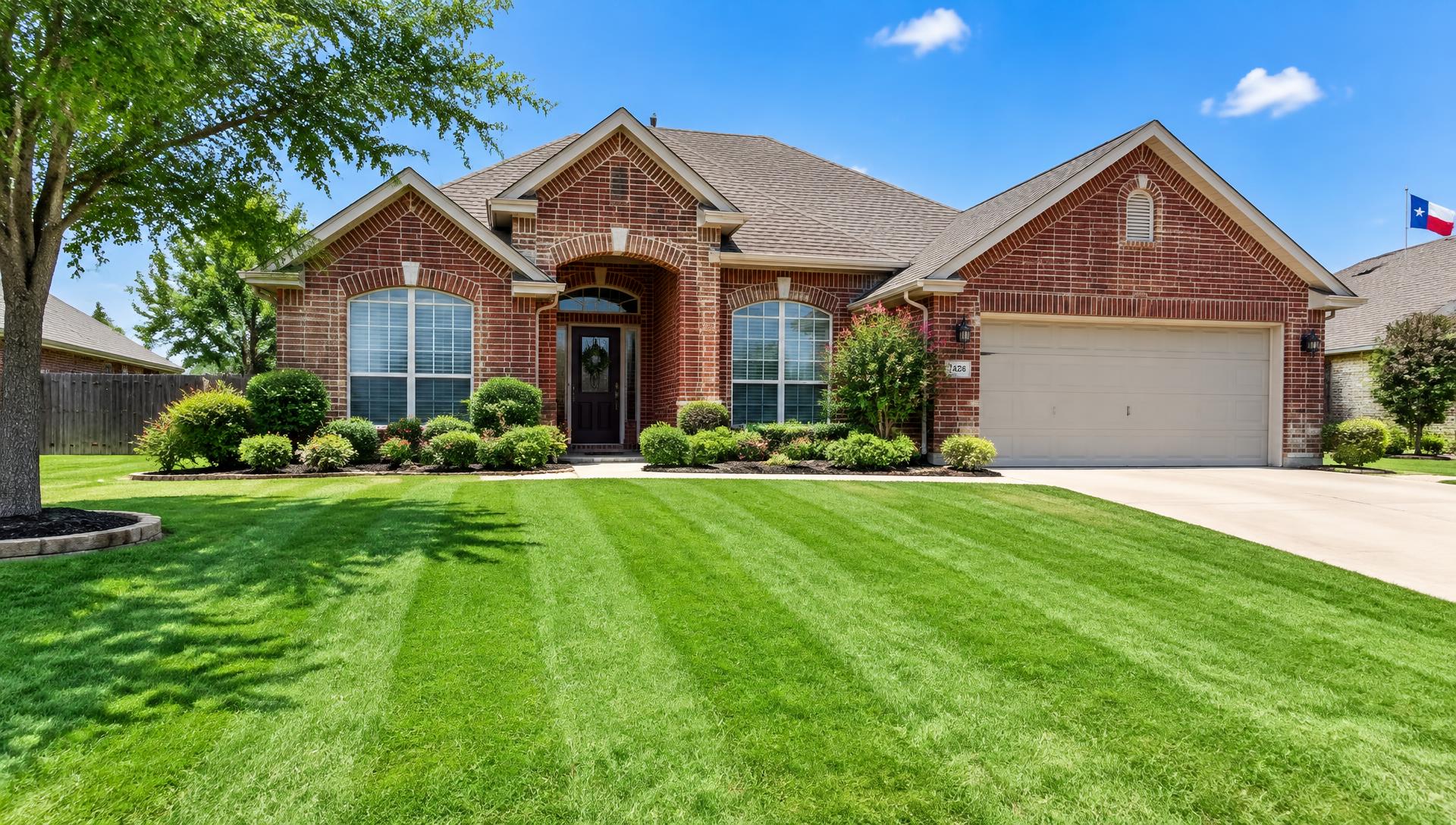 Freshly mowed striped lawn in front of a brick home in Fort Worth, TX